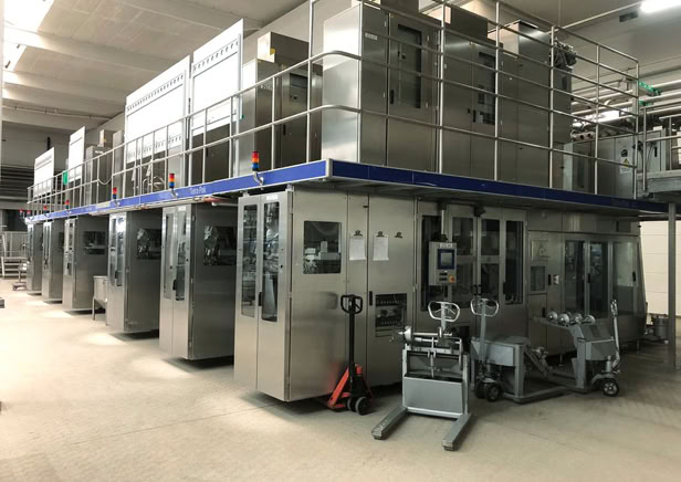 Industrielle Abfüllanlage mit mehreren großen Maschinen in einer Fabrikhalle.